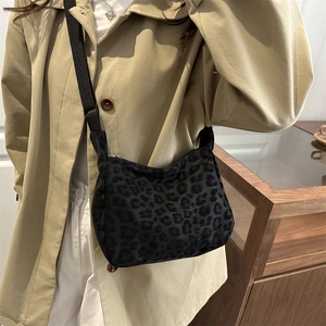 Fashionable leopard print tote bag with adjustable black strap worn over a khaki trench coat