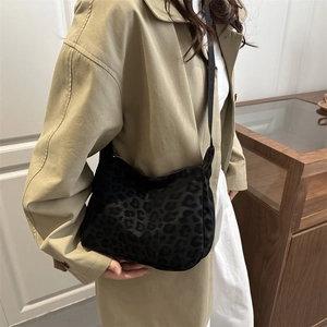 Leopard print hobo bag with adjustable strap worn by model over a beige trench coat