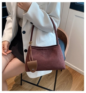 Détail du sac bandoulière en daim avec bandoulière nouée et pendentif en cuir élégant