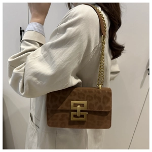 Detail of trendy leopard print bag featuring a gold interlocking metal buckle and chain strap