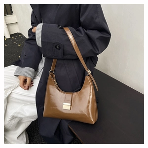 Close-up of brown textured leather bucket bag with adjustable strap and metal buckle