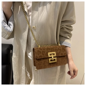 Detail of leopard print flap bag featuring a golden geometric lock and chain strap