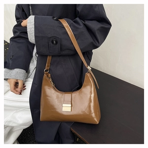Detail of a brown leather hobo bag with metal buckle on a dark wooden surface