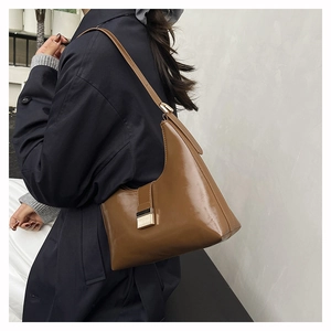 Detailed side view of the glossy brown leather croissant bag with metallic buckle detail