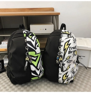 Detail of urban graffiti backpacks in green and black with astronaut charms on a shelf