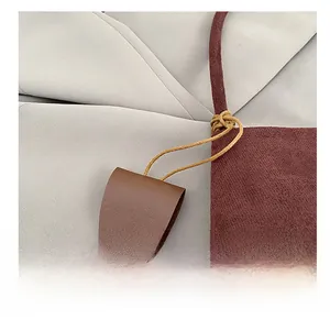 Detailed close-up of brown leather bag charm with silver metallic snap button and strap