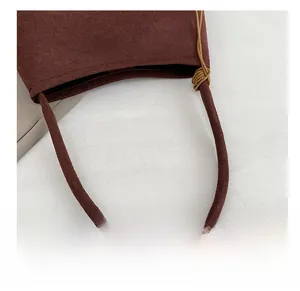 Detail of the thick padded shoulder strap with decorative cord wrapping on a brown suede bag