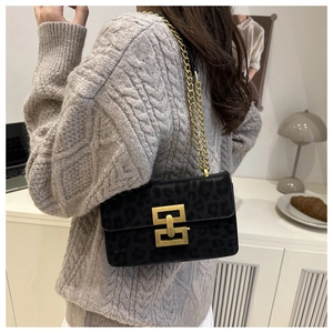 Detail of black leopard print suede crossbody bag with gold chain strap on model