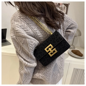 Detail of black leopard print suede crossbody bag with gold chain and metal buckle