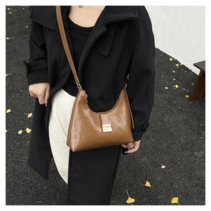 Brown leather hobo bag with metal buckle shown in a stylish autumn outfit perspective
