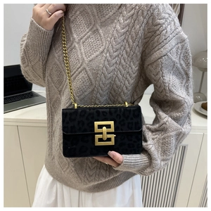 Detail of black leopard print flap bag featuring gold chain and metallic buckle