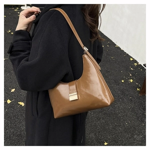 Detail of caramel vintage shoulder bag with golden buckle on elegant black coat
