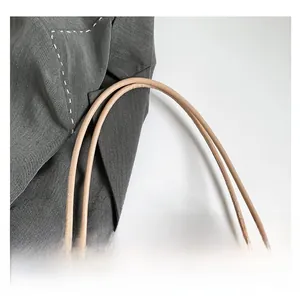 Détail d'un sac à main en peluche beige avec anses cylindriques en similicuir