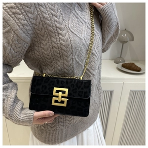 Detail of black leopard texture small square bag with gold metal buckle and chain strap
