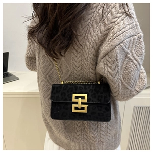 Detail of a leopard print crossbody bag with gold hardware and chain strap on a model