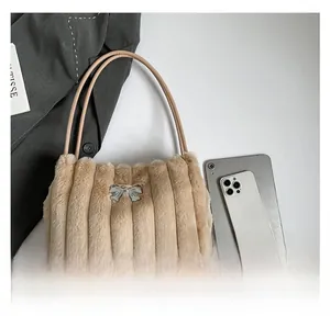 Détail du sac bandoulière en peluche beige avec surpiqûres verticales et nœud argenté
