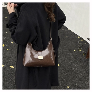 Detail of dark brown glossy crescent bag with gold buckle on a wool coat background