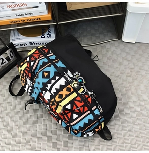 Detail of the colorful geometric ethnic print and astronaut charm on the black backpack