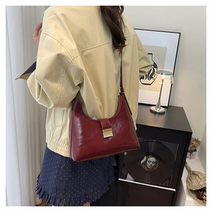Detail of burgundy glossy oil wax leather shoulder bag with gold square metal clasp