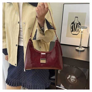 Detail of burgundy PU leather shoulder bag with sleek metal buckle and curved handle