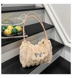Détail du sac à main en peluche beige avec plis verticaux et nœud argenté