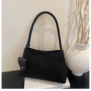Close-up of matte black underarm bag featuring a unique heart-shaped charm and spiral strap