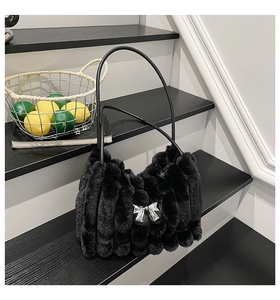 Détail d'un sac à main en fausse fourrure noire avec nœud argenté et textures