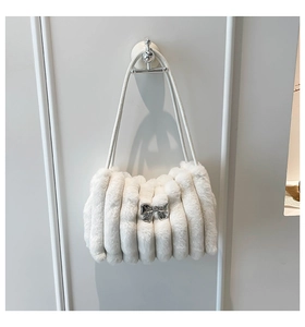 Détail du sac à main en peluche blanche avec matelassage vertical et nœud en métal argenté