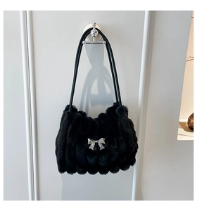 Détail du sac d'épaule en fausse fourrure noire avec nœud argenté et texture côtelée