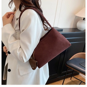 Deep brown suede shoulder bag styled with a white suit and matching mini charm