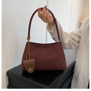 Brown suede underarm tote bag with long shoulder straps and metallic charm detail