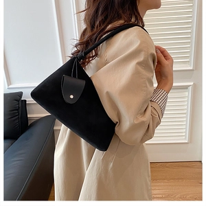 Détail du sac bandoulière en daim noir avec bandoulière nouée et porte-cartes décoratif