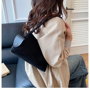 Detail of minimalist black fabric underarm bag with leather flap and silver buckle closure