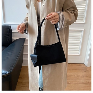 Detail of black suede shoulder bag with detachable mini pouch on a stylish trench coat