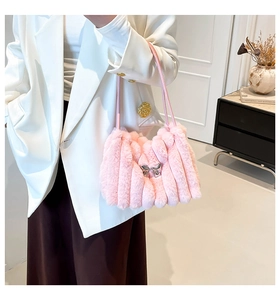 Sac fourre-tout rose en peluche avec nœud argenté porté sur un blazer blanc