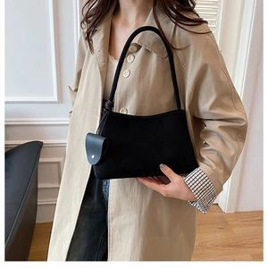 Minimalist black shoulder bag with matching coin purse shown on khaki trench coat