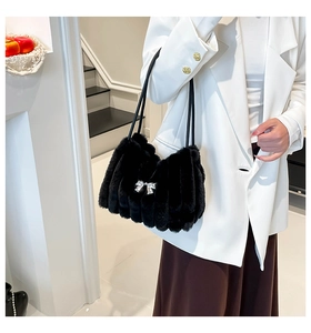 Détail du sac à main en fausse fourrure noire avec plis verticaux et nœud en métal argenté