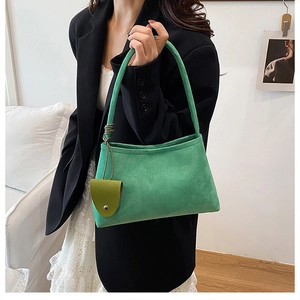 Sac à épaule en daim vert herbe avec breloque triangulaire porté par un mannequin