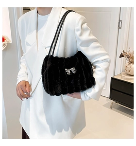Détail du sac d'épaule en fausse fourrure noire avec boucle nœud argenté sur costume blanc
