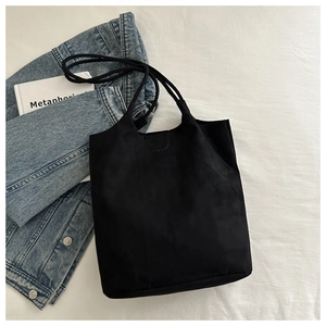 Detail of minimalist black tote bag with long straps paired with denim for daily style