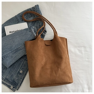 Brown suede tote bag with large capacity and magnetic clasp on white fabric background