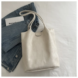 Detail of minimalist cream suede shoulder bag with magnetic snap and long handle straps