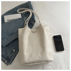 Detail of off-white faux suede tote bag with magnetic clasp on a casual flat lay