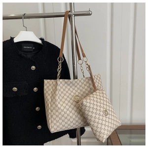 Detail view of tote bag set with monogram print, brown leather straps and gold logo charm