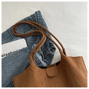 Overhead view of a brown suede tote bag with slim straps on a white background