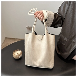 Close-up of beige suede tote bag with minimalist strap and elegant decorative buckle