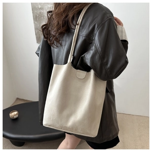Minimalist beige suede bucket bag with magnetic closure for women shown on model