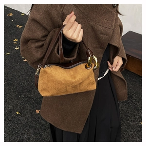 Detail of vintage brown suede baguette bag with leather strap and gold buckle