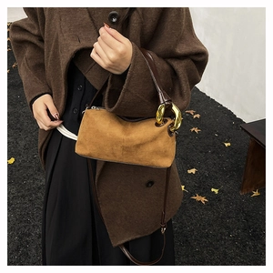Close-up of brown matte suede cylinder bag featuring gold metal chain and leather handle