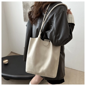 Model wearing beige suede bucket bag with long shoulder strap for casual commute style